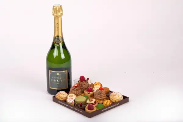 Une bouteille de Champgne avec un petit plateau de petits fours sucrés.