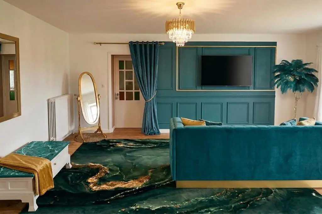 Espace salon de la suite Art Déco au Domaine d'Angély, comprenant un large canapé en velours bleu canard, une télévision écran plat intégrée dans des boiseries vert sombre, un lustre en cristal et un miroir psyché doré sur un tapis artistique effet marbre.