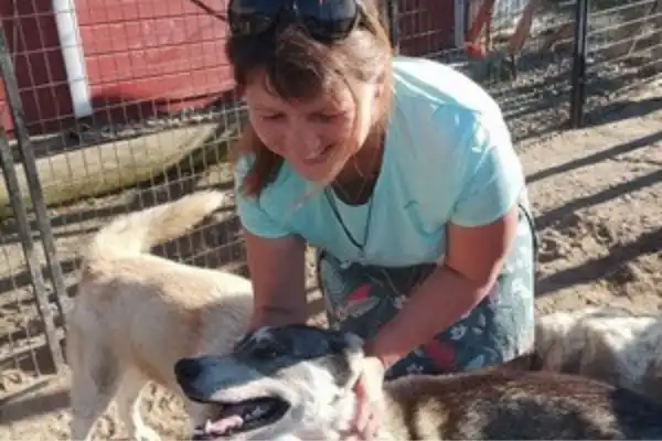Photo de la directrice du Domaine d'Angély, entourée de chiens heureux et complices, montrant son professionnalisme et son affection. Elle est titulaire de l'ACACED.