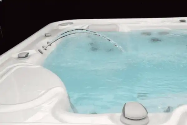 Gros plan sur les jets d'eau d'un jacuzzi moderne projetant des arcs d'eau claire dans une eau turquoise bouillonnante, évoquant le bruit relaxant de la source.