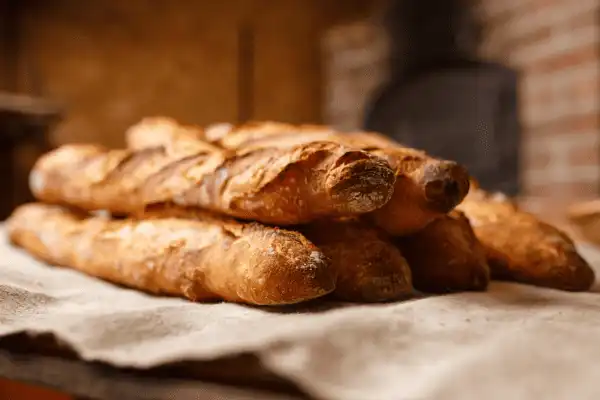 Piles de baguettes de tradition française fraîches et croustillantes, posées sur un linge en lin, livrées par la boulangerie Le Délice des Anges pour le Domaine d'Angély.