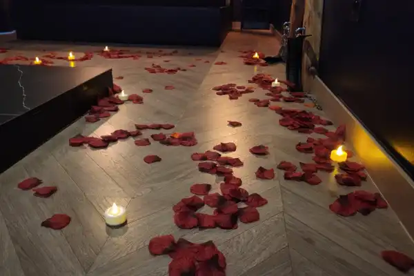 Un sol sombre éclairé par des bougies recouvert d'un chemin de pétales de roses rouges.